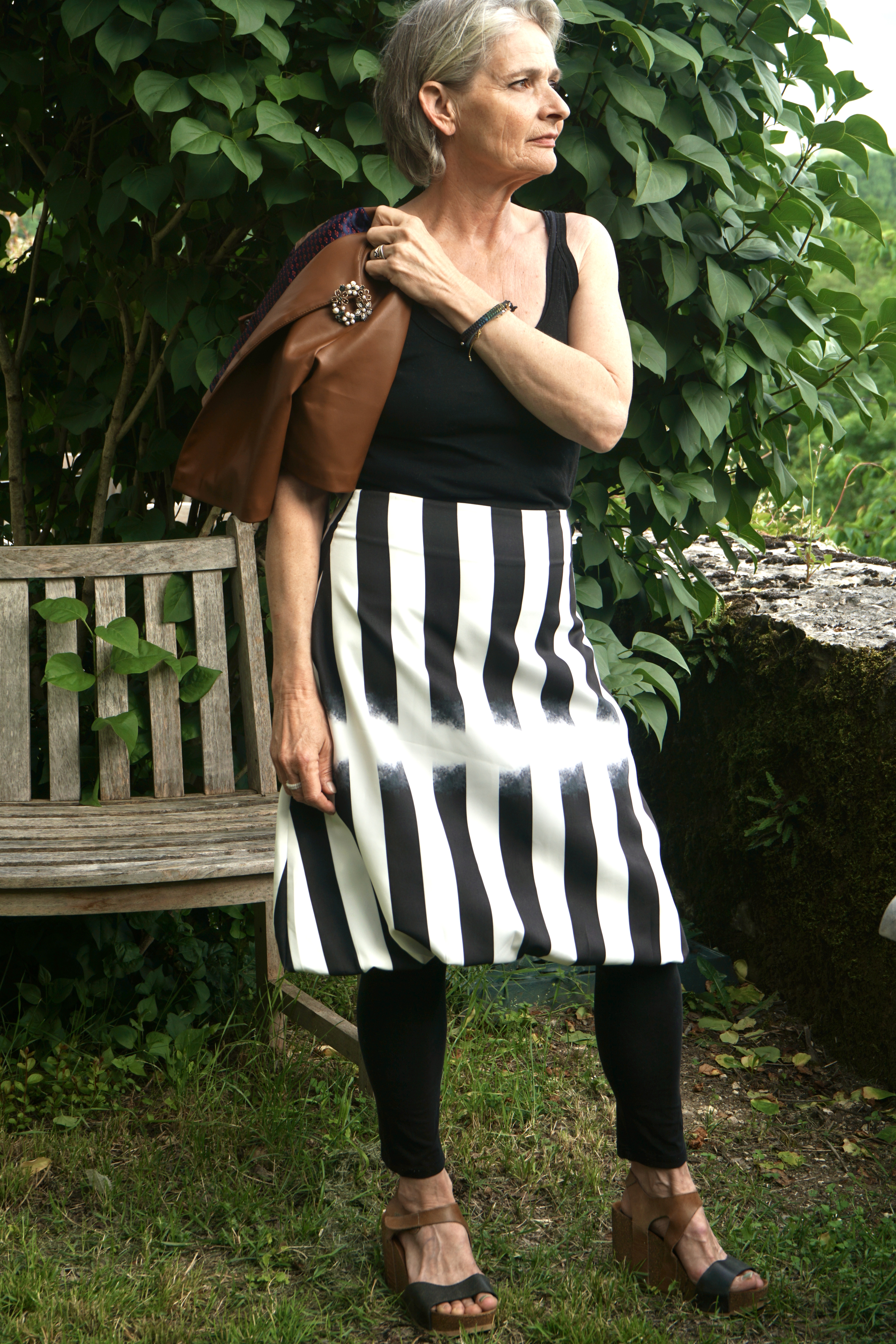 Mannequin en jupe rayée noire et blanche, veste sur l'épaule.