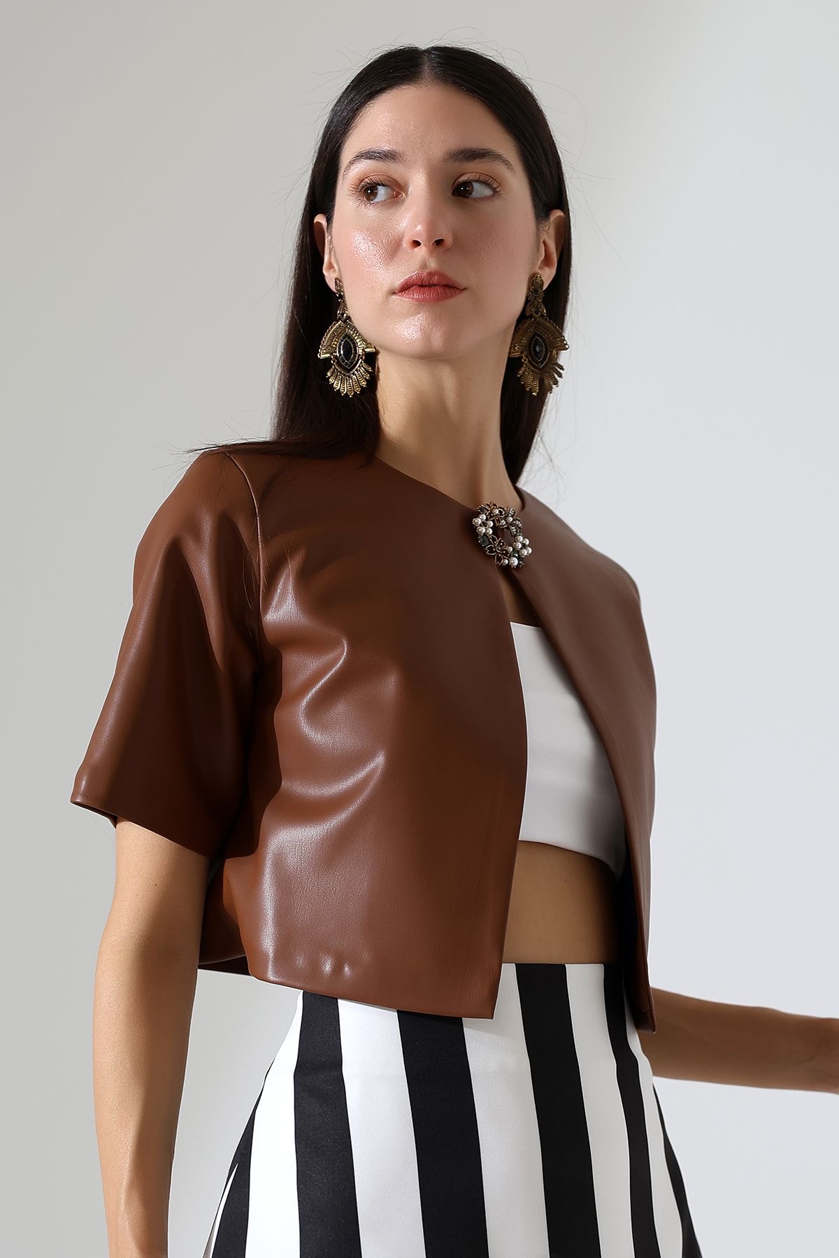 Gros plan sur un mannequin en jupe rayée et veste à manches courtes en cuir beige