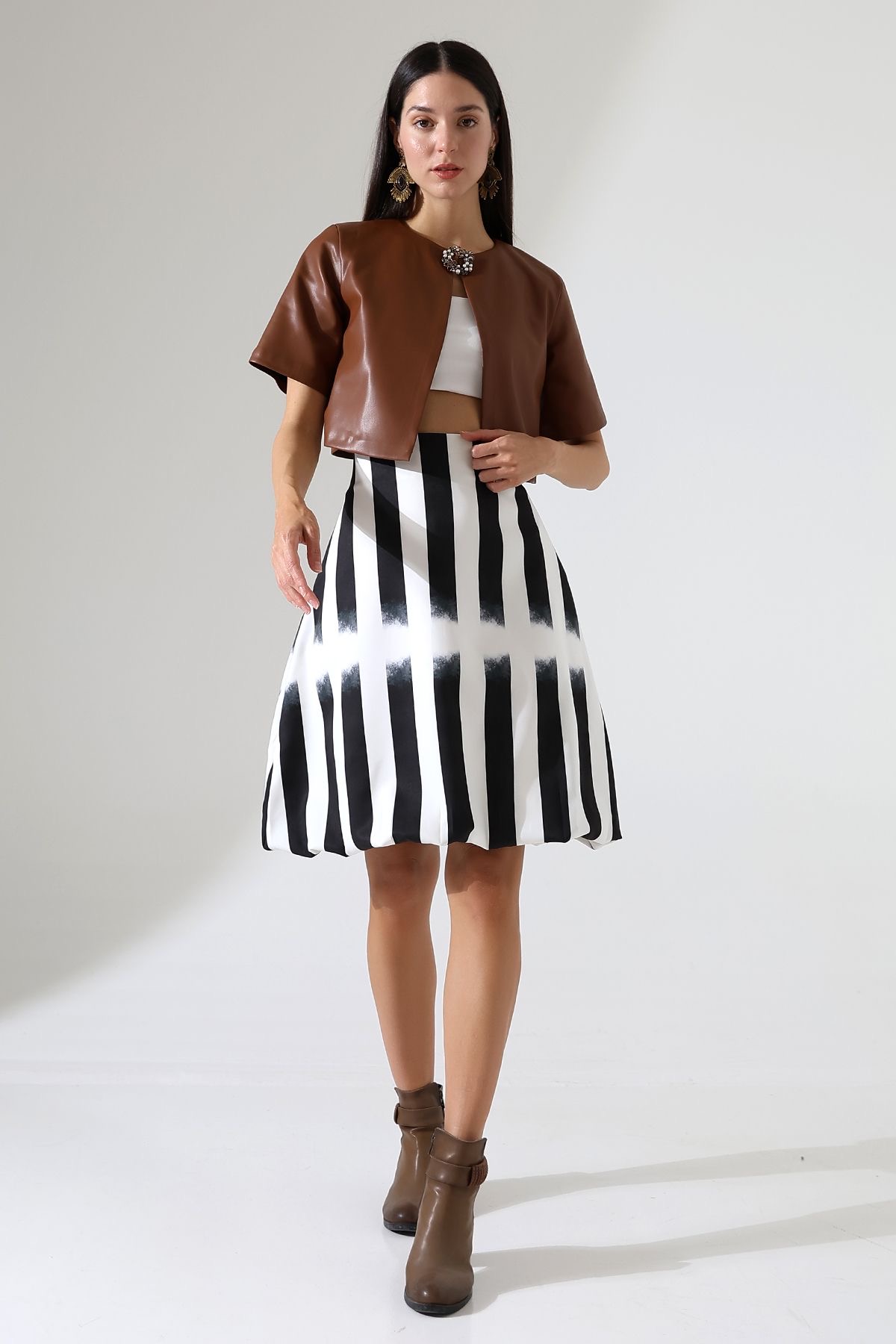 Vue d'ensemble du mannequin en jupe rayée et veste en cuir beige à manches courtes.