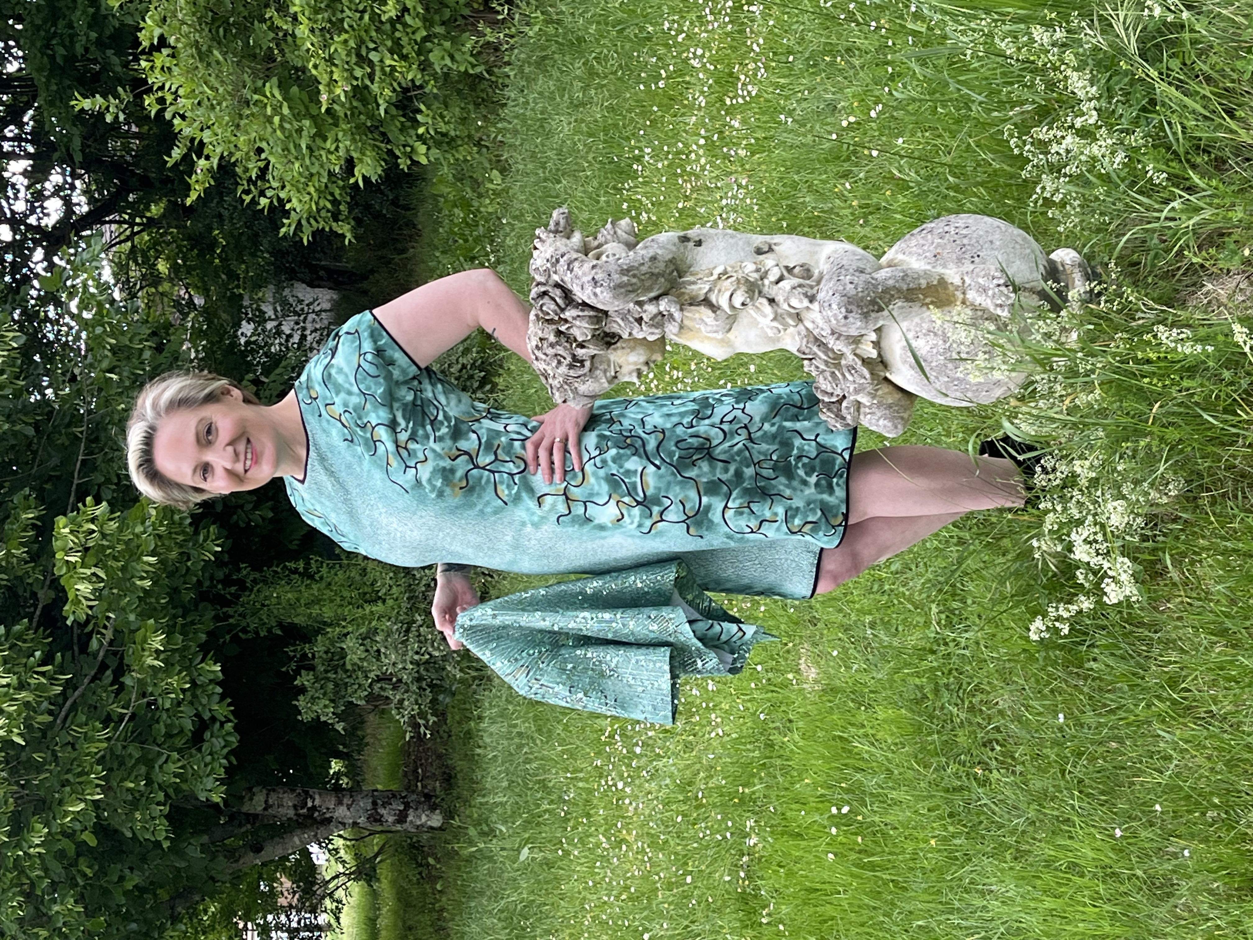 Vue d'ensemble extérieure, près d'une statue, d'une robe de soirée verte courte et d'un boléro