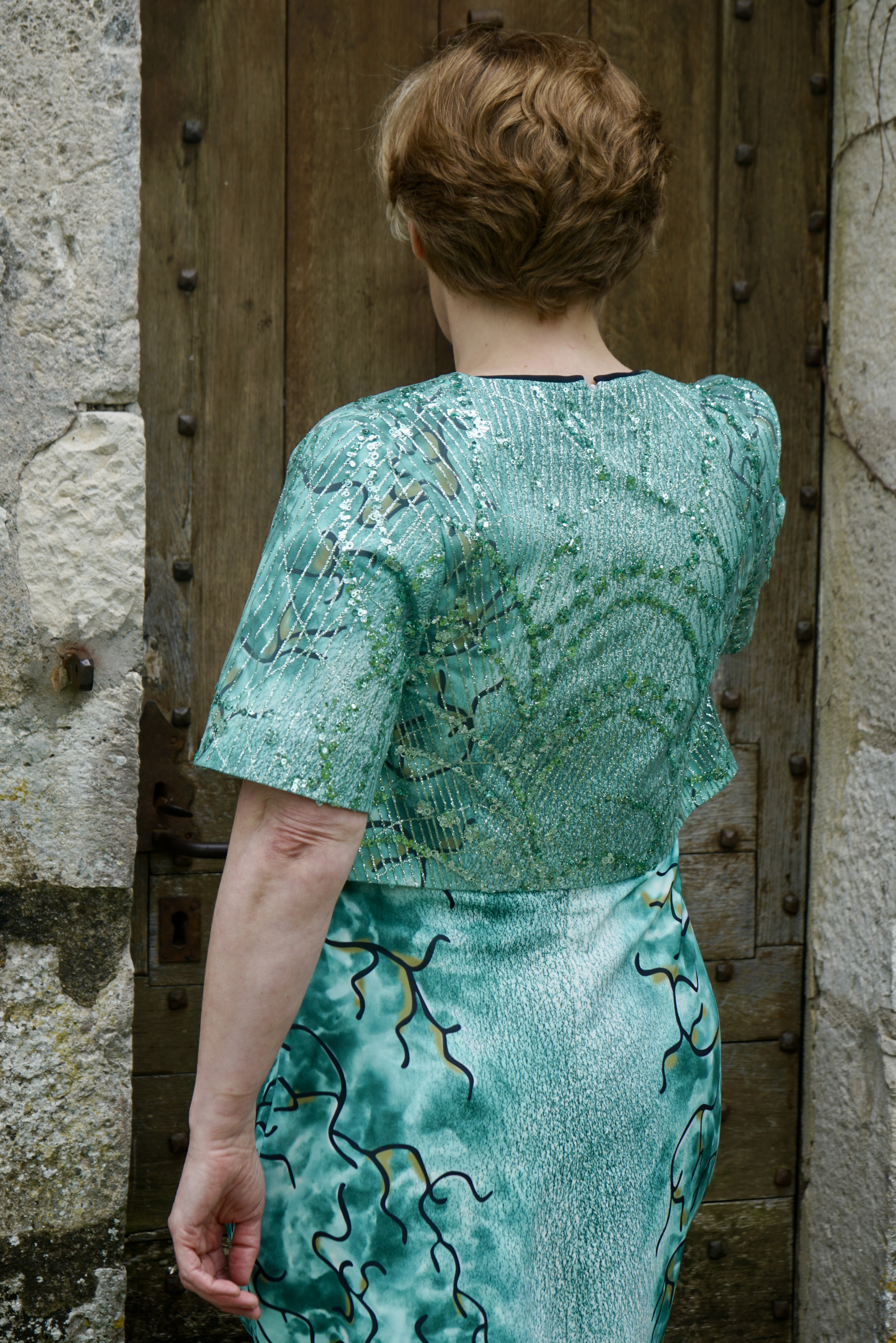 Dos de la robe verte à motifs et de la veste nacrée