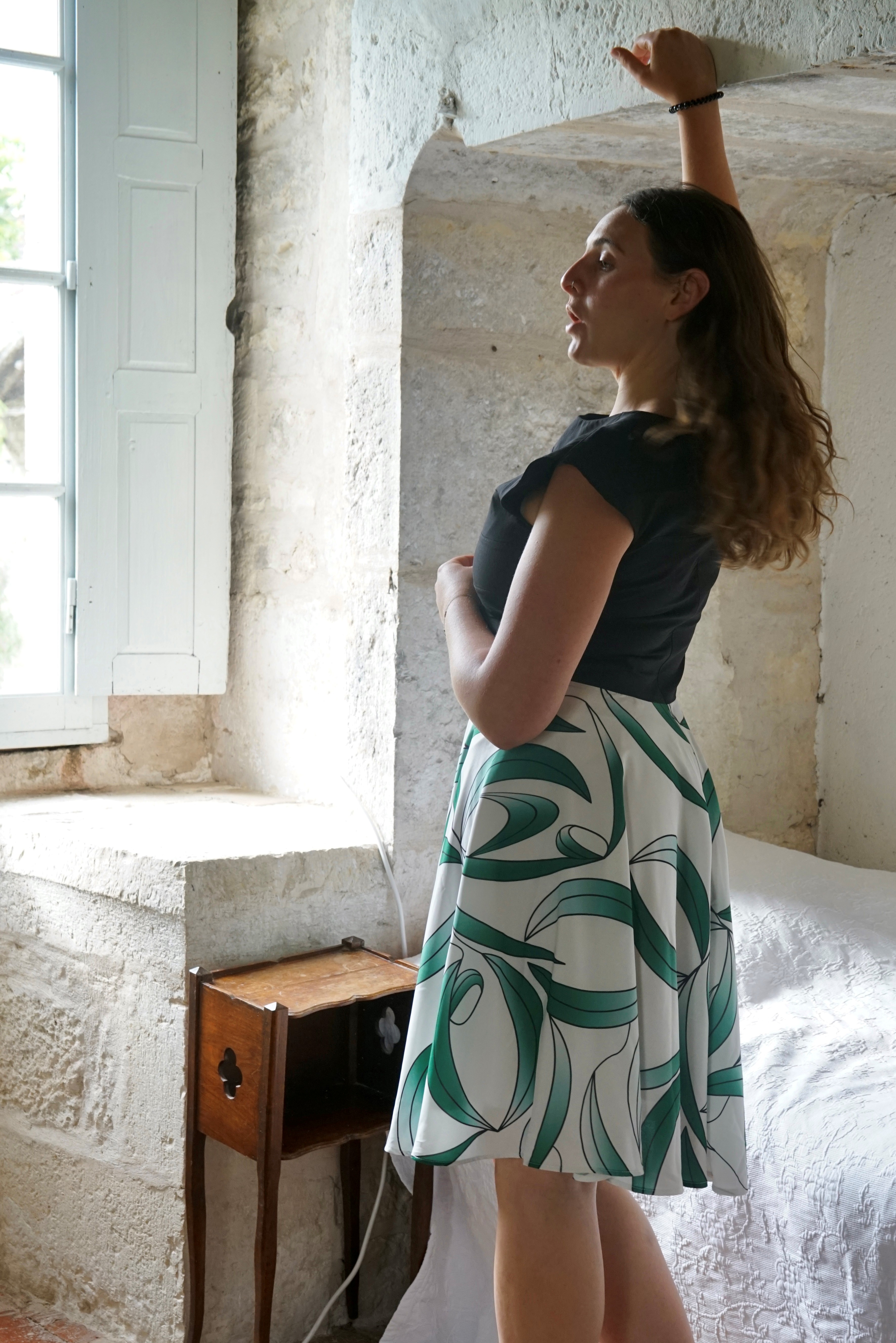 Vue de dos du mannequin en robe noire avec jupe à motifs blancs et vert feuille