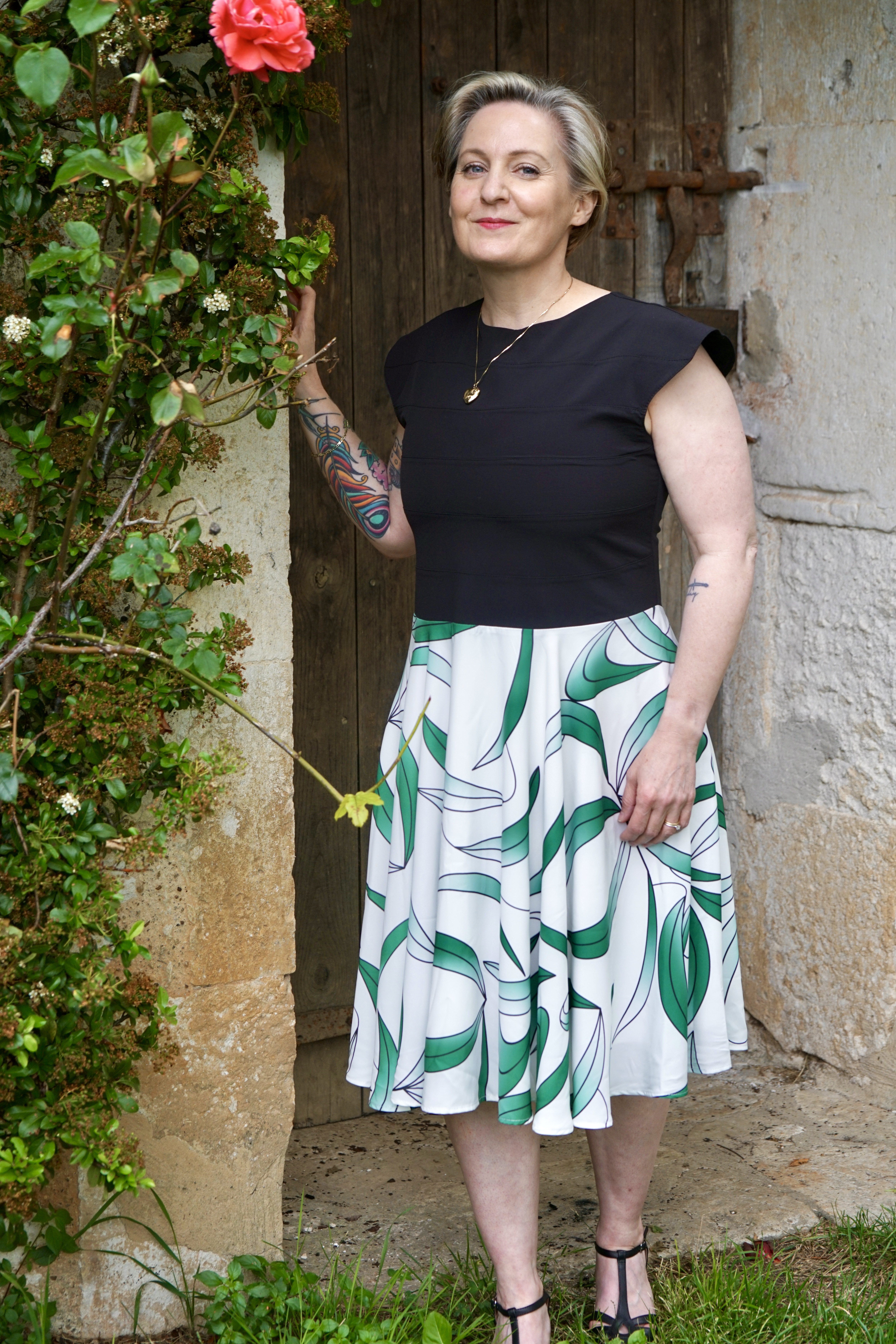 Mannequin portant une robe noire avec un haut et une jupe blanche et vert feuille à motifs